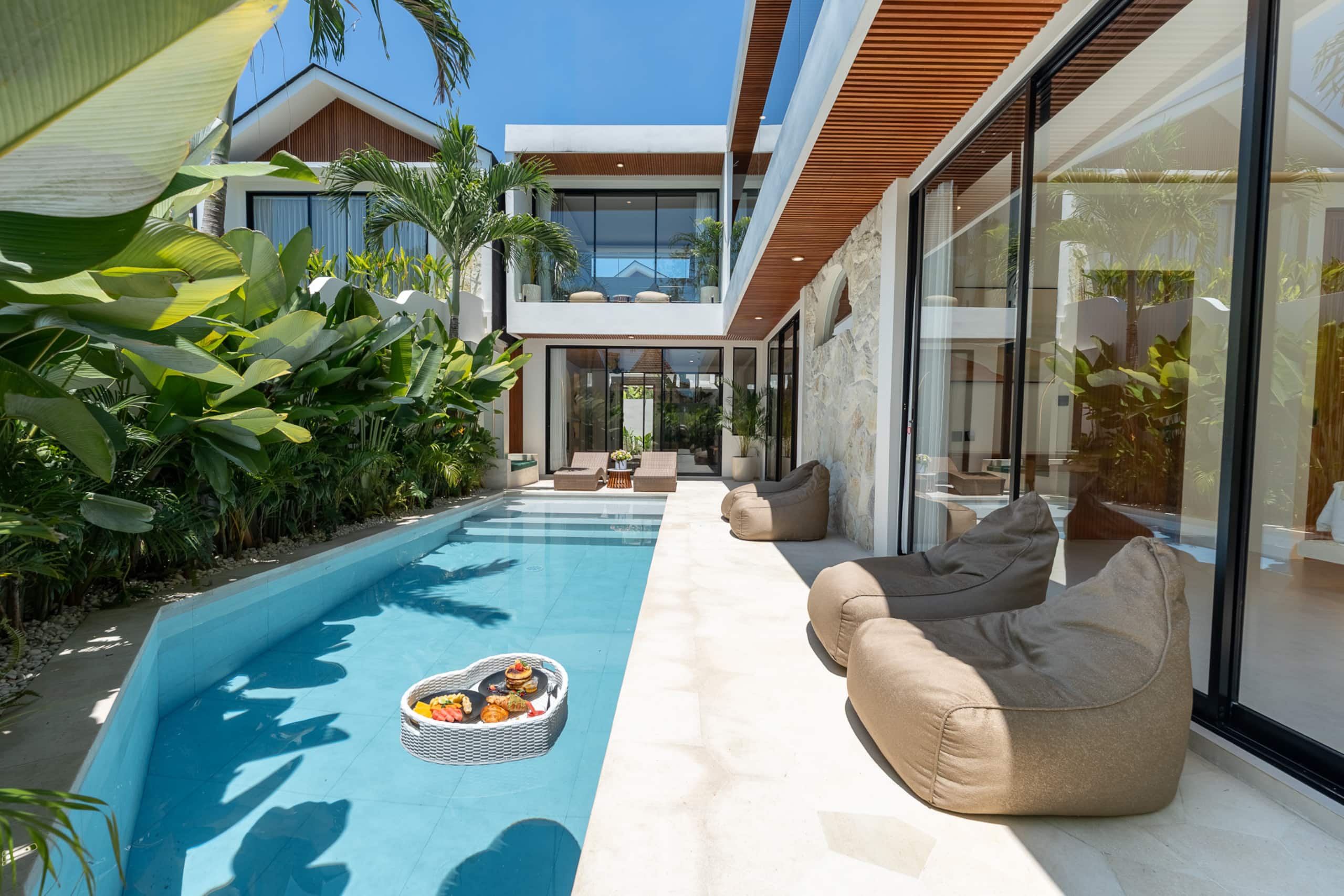 Pool, loungers and glass front of Elva 6 in daylight